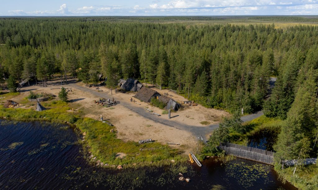 A model of a Stone Age village has been constructed along the Iijoki River in Kierikki.The picture is taken from the air. There are six houses in a row on a sandy beach alongside the river Iijoki.